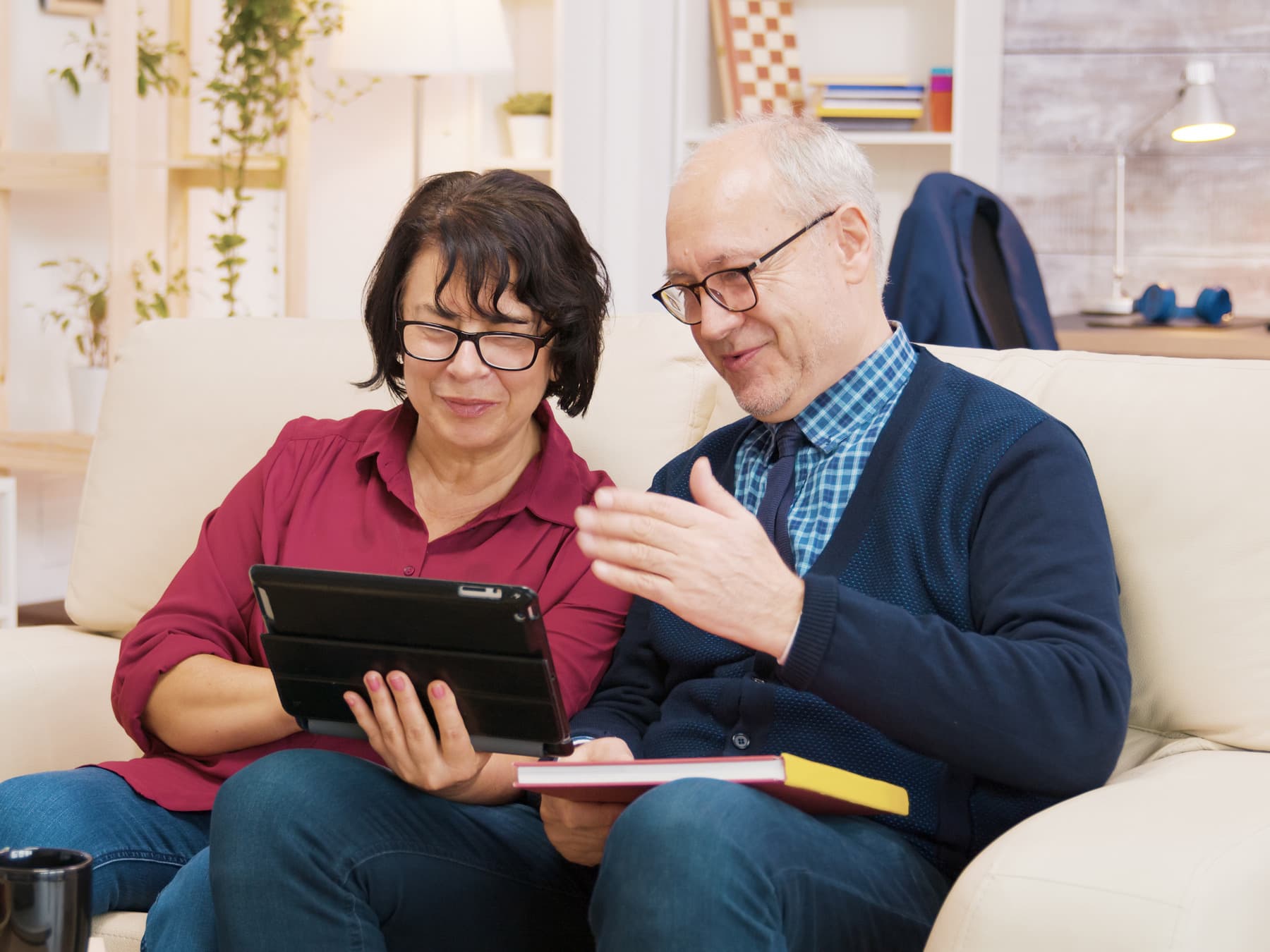 An older couple sitting together on a sofa at home, following a session on a tablet.